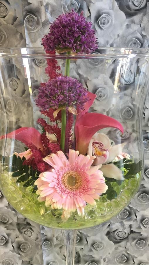 Un jarrón de cristal lleno de flores rosas y moradas.