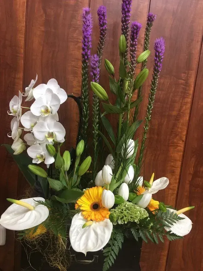 Un jarrón lleno de flores está sobre una mesa de madera.