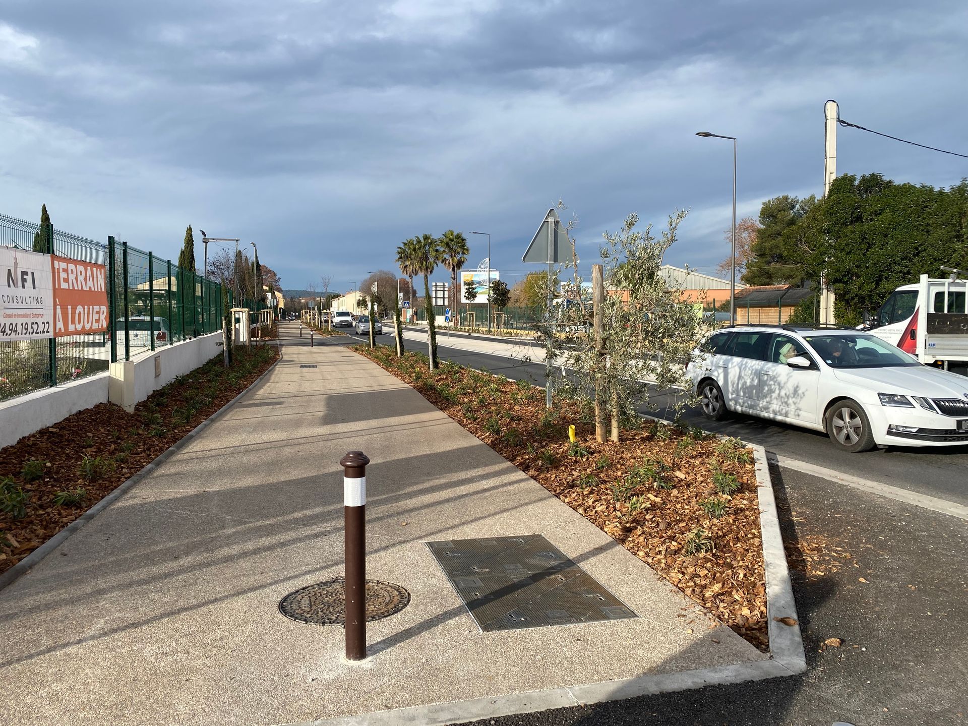 Trottoir pavé bordant une route paysagée.