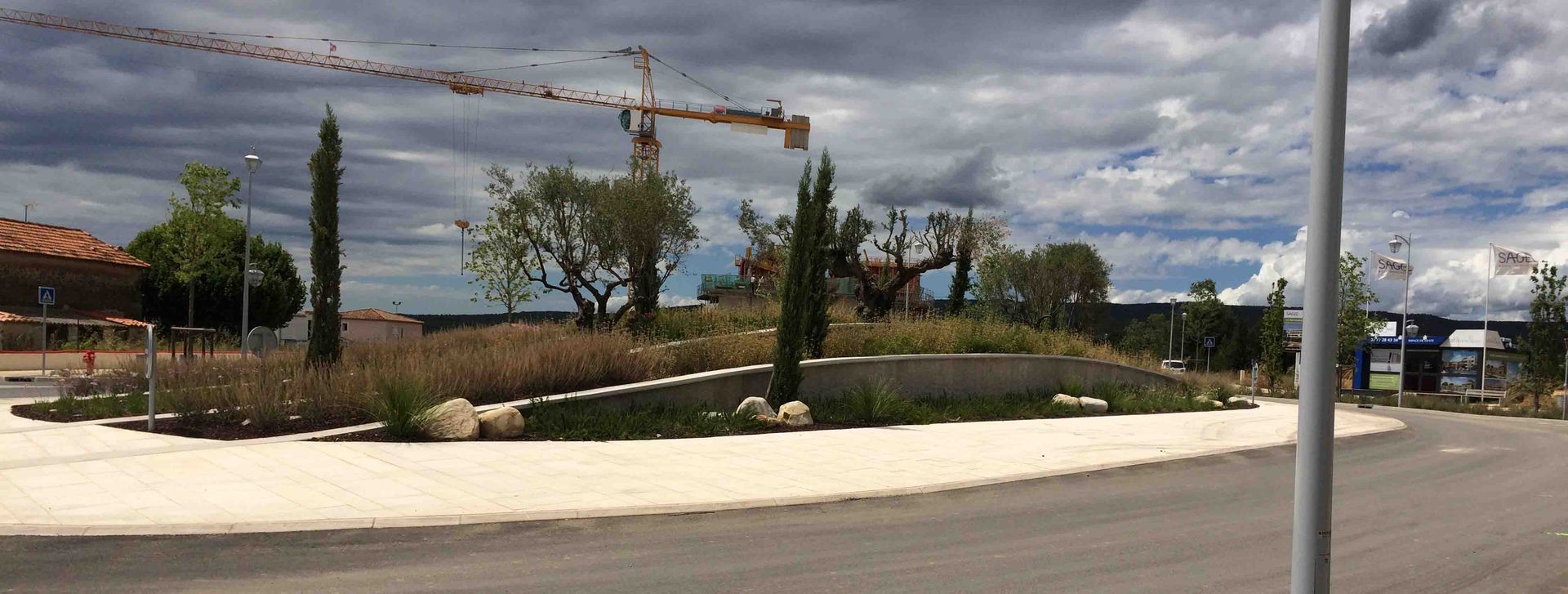 Vue panoramique d'un chantier de construction avec des grues et des arbres.