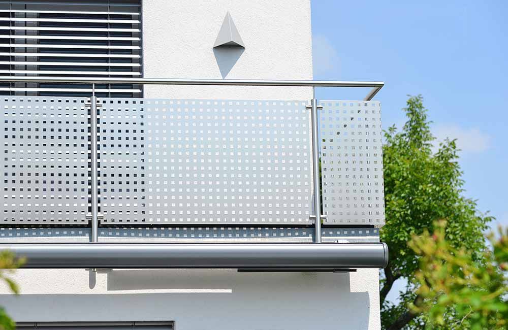 ein Balkon mit einem Edelstahlgeländer an der Seite eines Hauses.