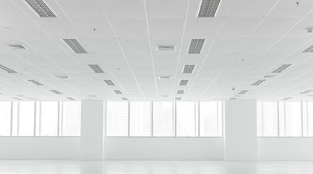 Una oficina vacía con muchas ventanas y paredes blancas.