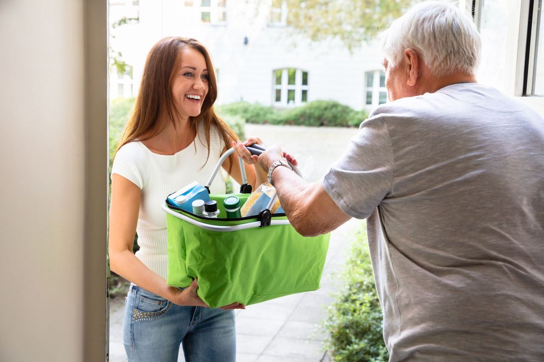 Une personne apporte les courses à une personne âgée