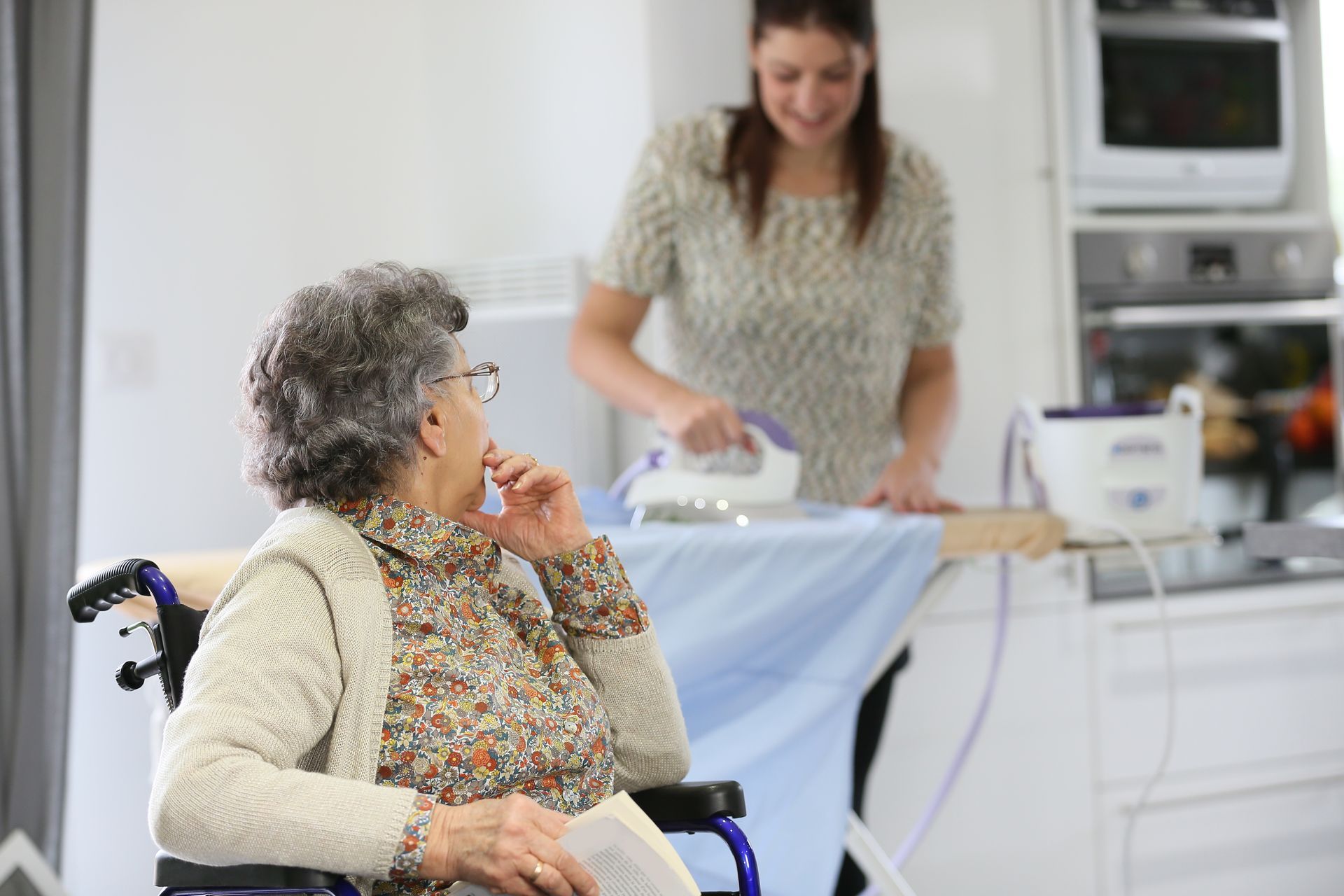 Une assistante repasse les vêtements d'une personne en fauteuil roulant