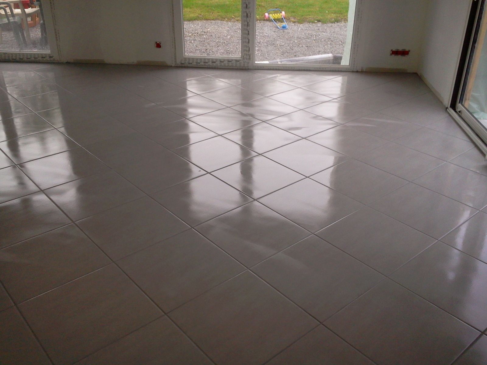 Sol carrelé clair et brillant à motif de losanges dans une pièce intérieure.