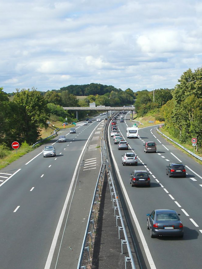 Autoroute avec des voitures circulant sur plusieurs voies sous un ciel nuageux.