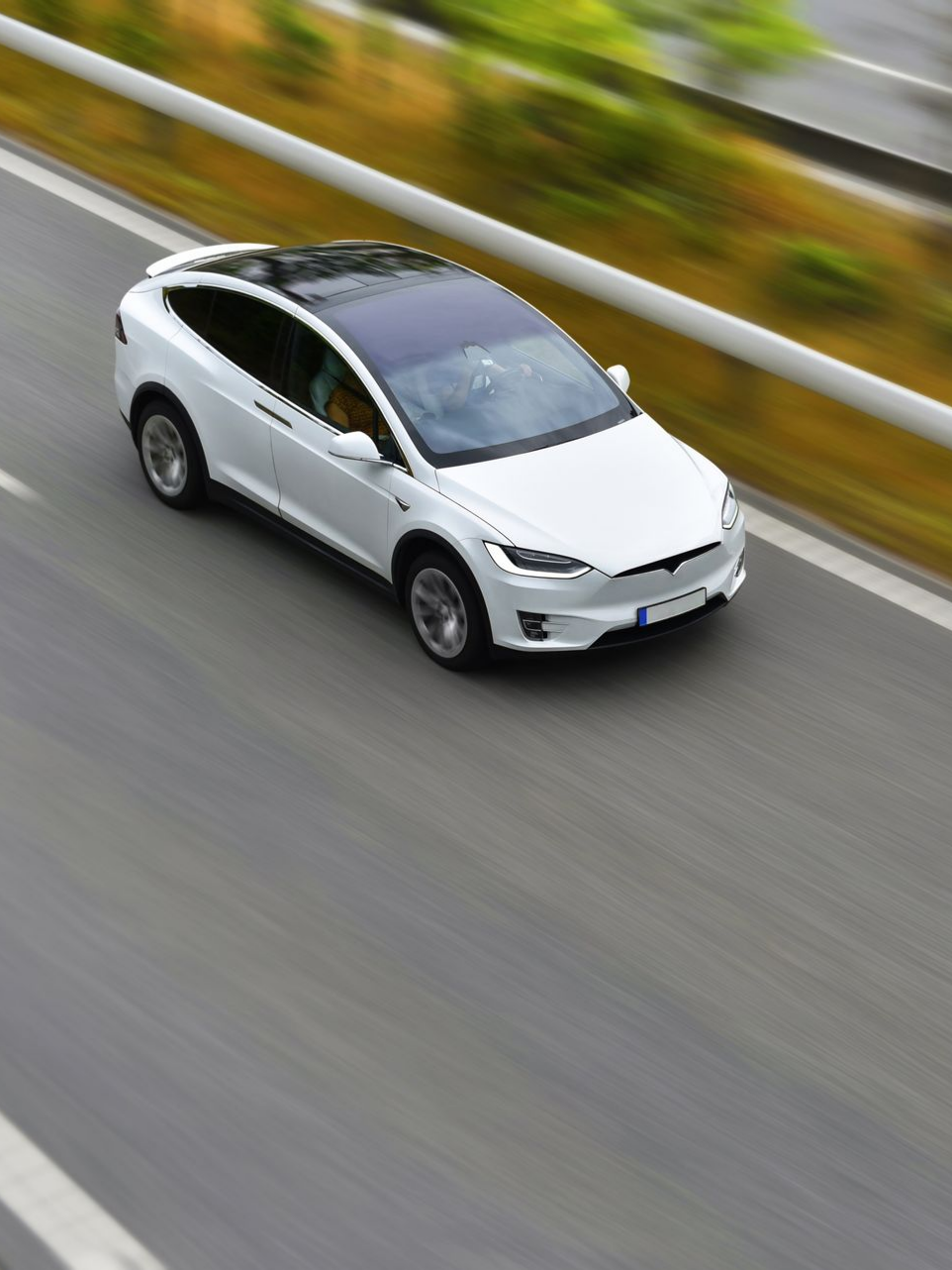 Voiture électrique blanche roulant sur une route asphaltée grise.