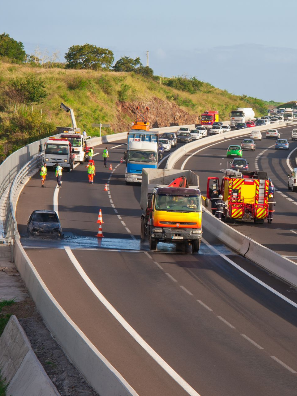 Scène d’embouteillage sur l'autoroute, avec véhicules d’urgence et secouristes, à la suite de l’embrasement d’un véhicule.