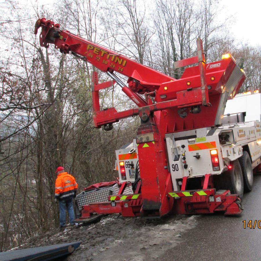 Dépanneuse avec grue déployée sur un parking, près d'une voiture dont la roue est immobilisée par un sabot.