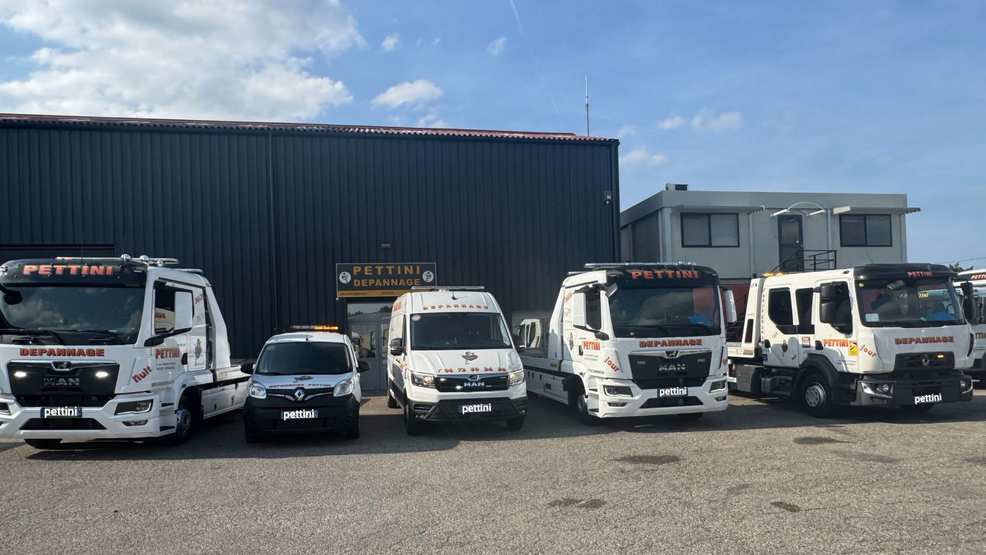 Plusieurs dépanneuses blanches stationnées devant un bâtiment.