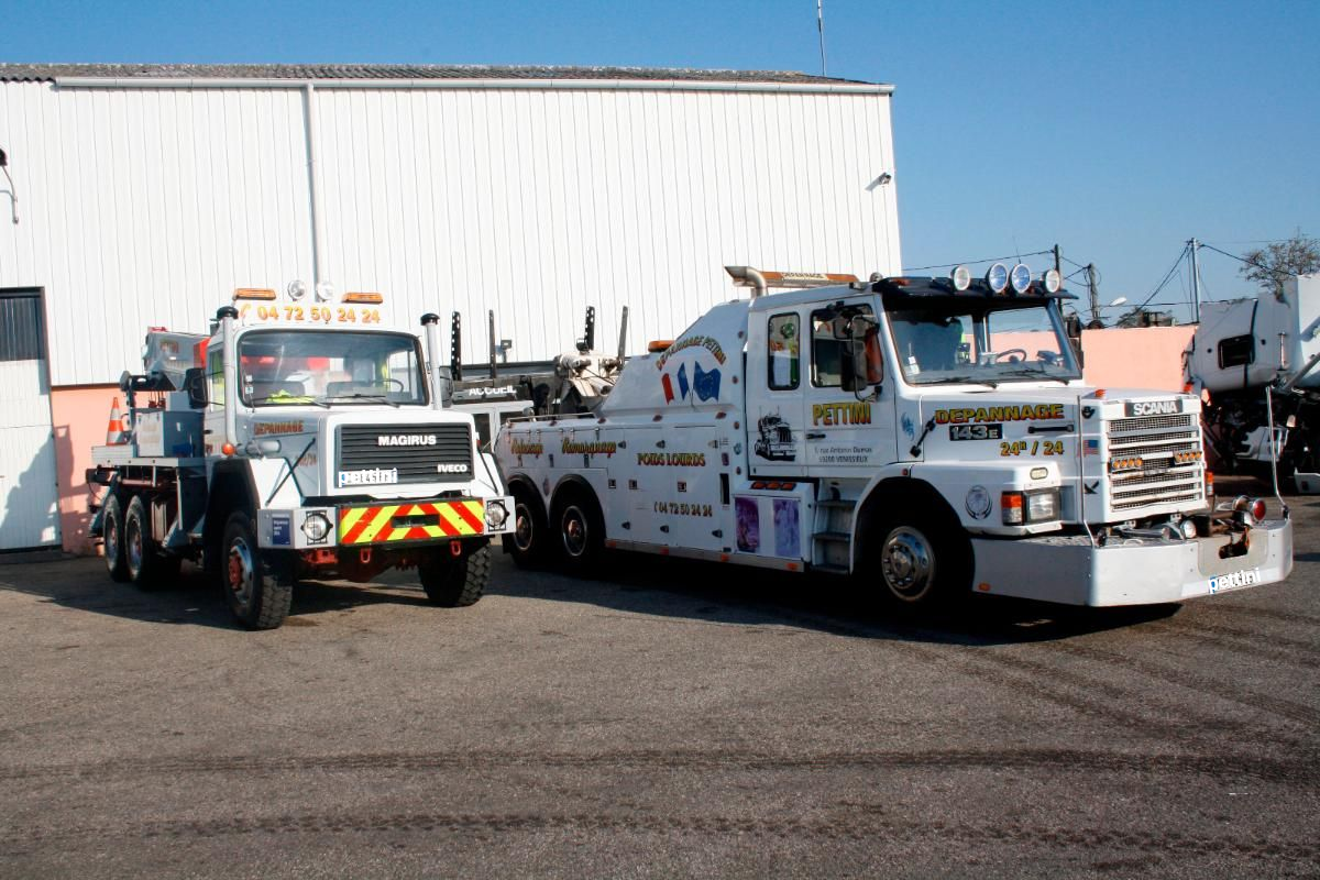 Deux dépanneuses blanches garées devant un bâtiment par une journée ensoleillée.
