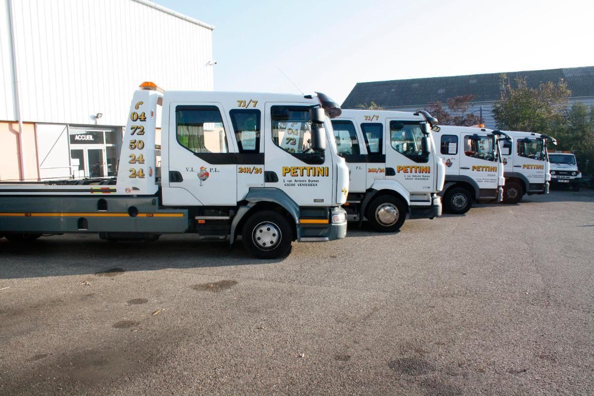 Plusieurs dépanneuses blanches stationnées devant un bâtiment.
