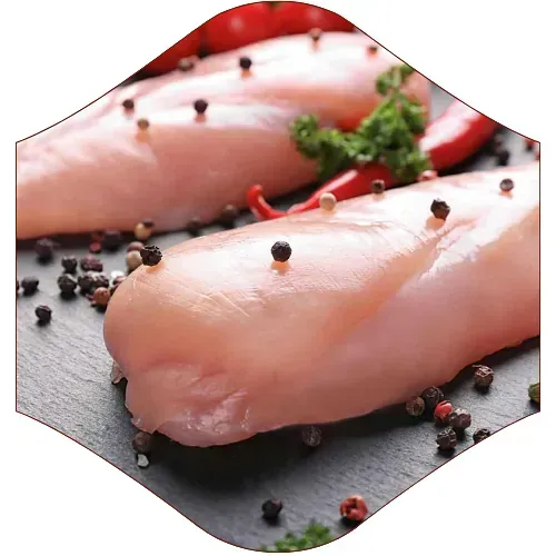 Un primer plano de pechugas de pollo con granos de pimienta sobre una mesa.