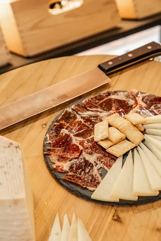 Hay un plato de carne y queso en una mesa de madera.