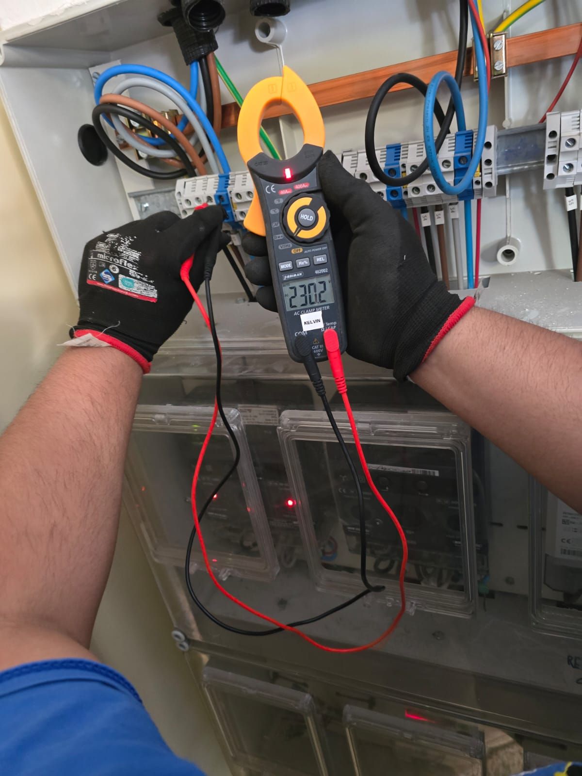 Un hombre está usando una pinza amperimétrica para probar un cable.
