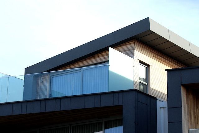 Una casa moderna con balcón y barandilla de cristal.