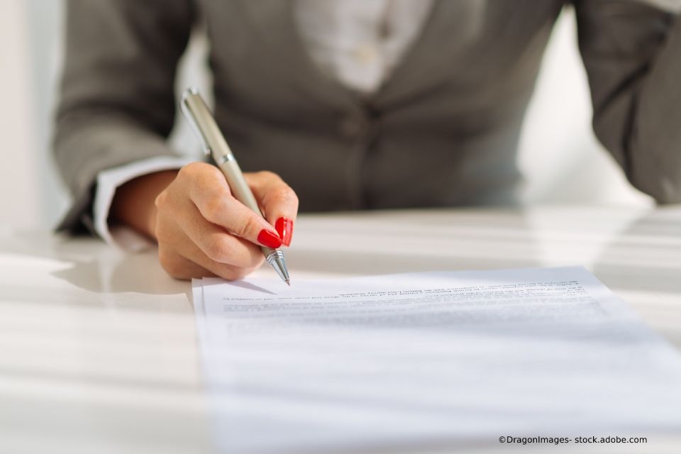 Rechtsanwältin Pia Grohmann Anwalt steht mit verschränkten Armen vor einem Bücherregal