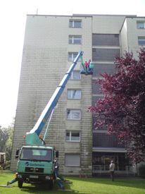 Fassade an einem mehrstöckigen Mehrfamilienhaus, die gerade von Betec GmbH gereinigt wird.
