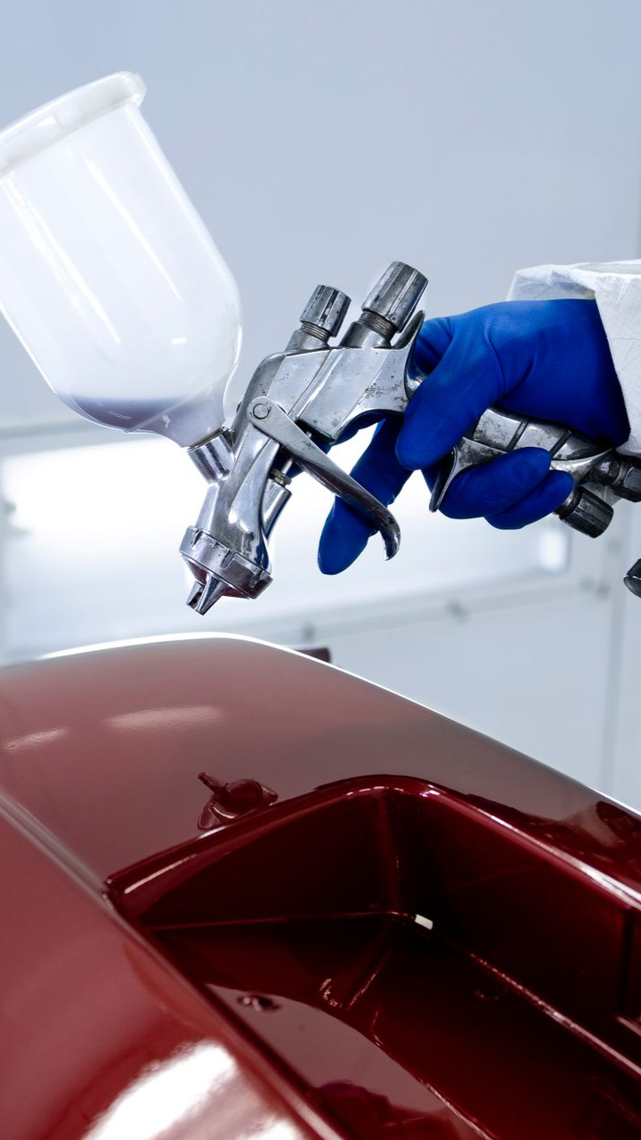 Homme qui peint une pièce de carrosserie