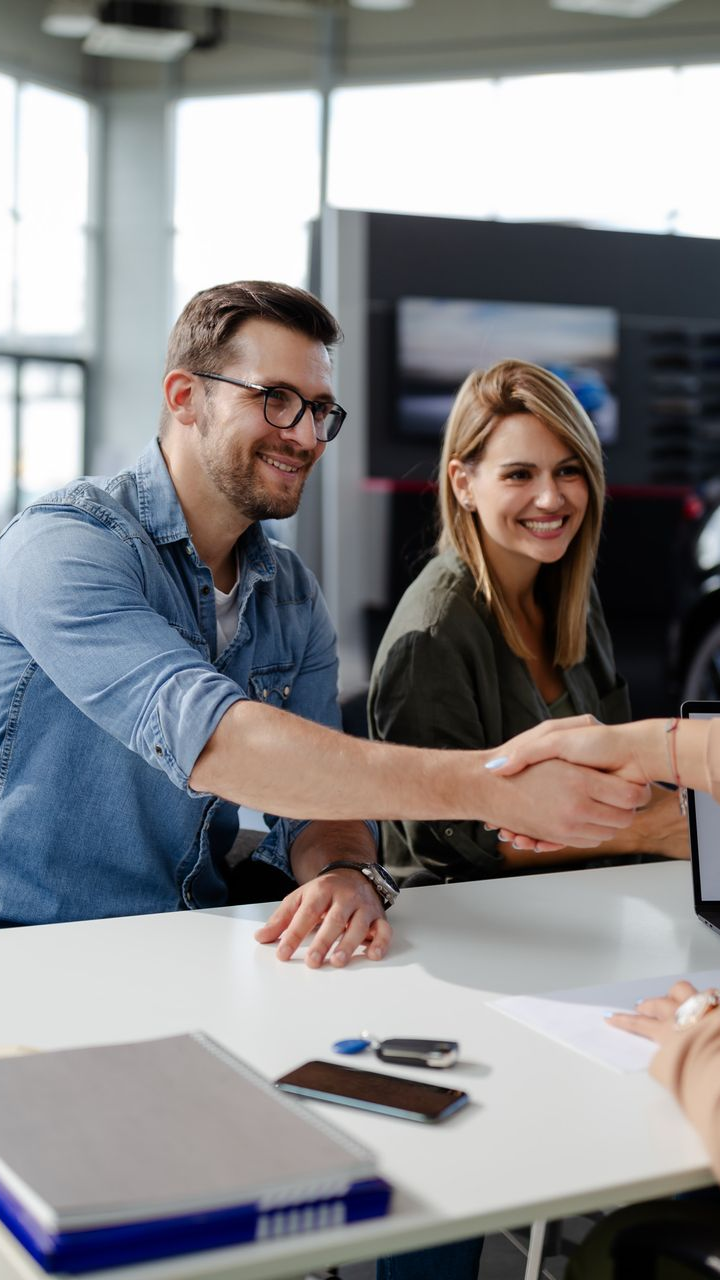 Poignée de main entre un homme et une femme à la suite d'une vente de voiture