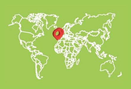Mapa mundial con una chincheta roja sobre el Reino Unido. Fondo verde y contornos blancos.