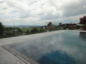 Modernes Schwimmbecken im Garten mit Blick auf angrenzende Felder