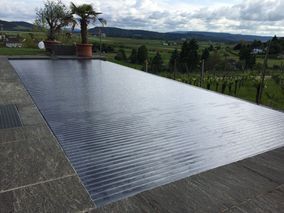 Modernes Schwimmbecken draussen im Garten mit Blick auf Felder und Berge