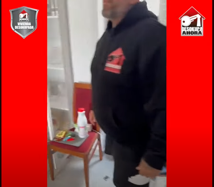 Un hombre con una sudadera con capucha negra está de pie en una habitación.