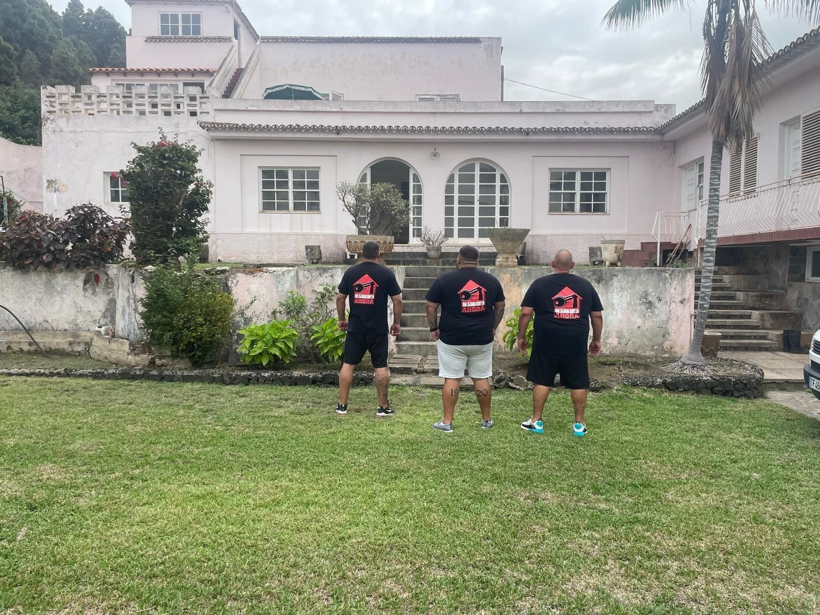 Tres hombres están parados frente a una casa grande.