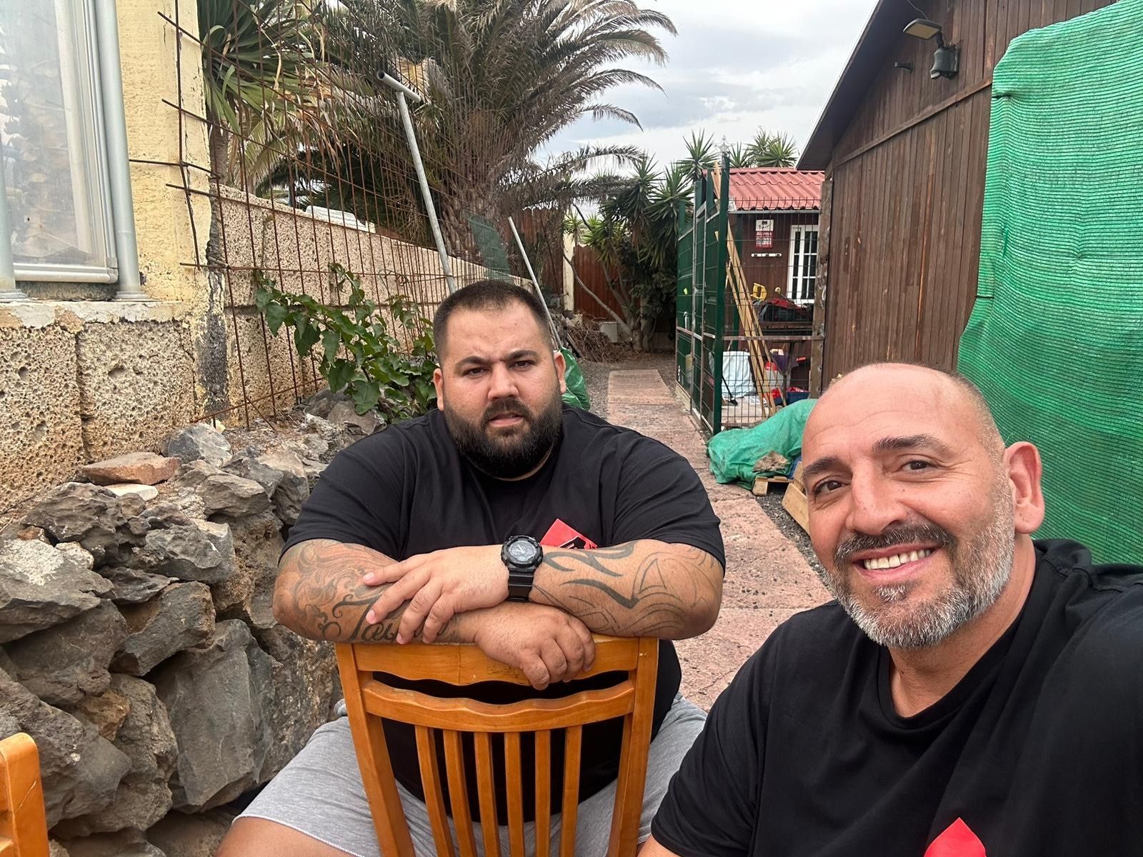 Dos hombres posan para una fotografía mientras están sentados en una mesa.