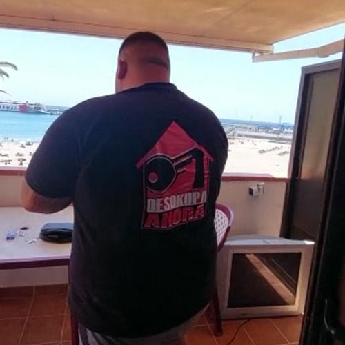 Un hombre parado en un balcón con una camiseta de Desokupa Aurora.