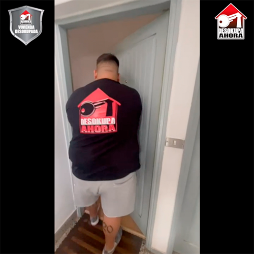 Un hombre que lleva una camisa negra con una casa roja y una llave en ella.