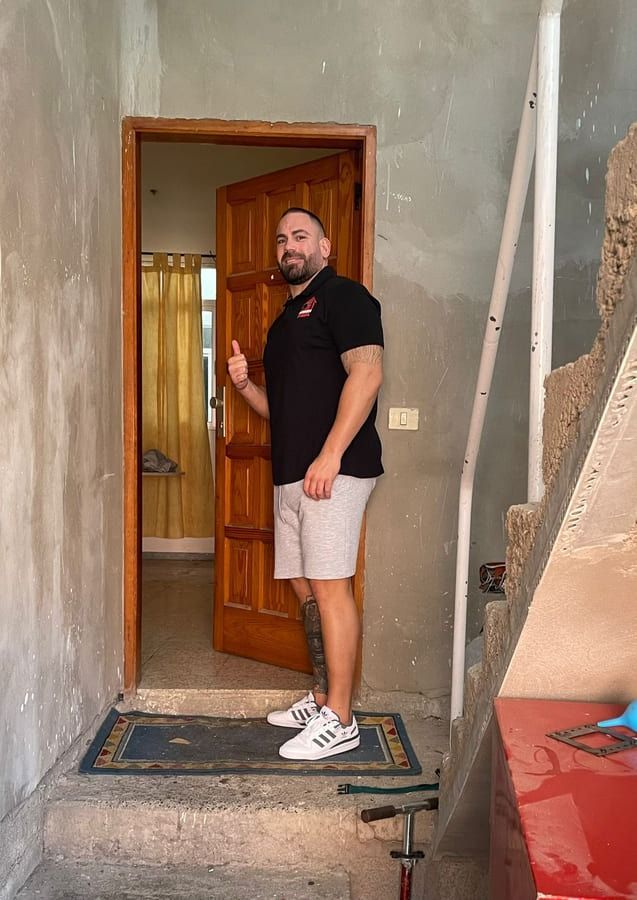 Un hombre está parado frente a una puerta haciendo un gesto de aprobación con el pulgar.