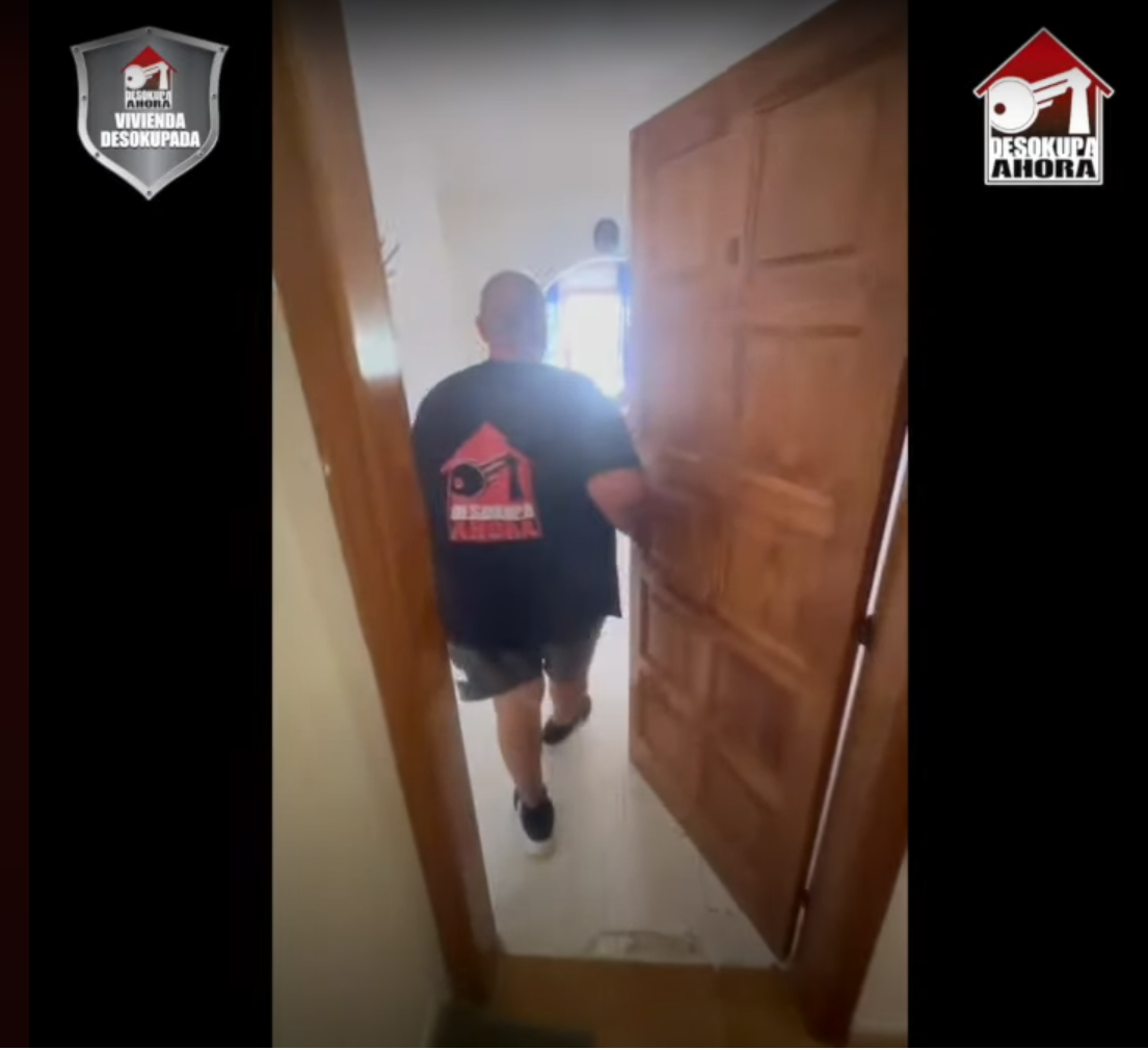 Un hombre con una camisa negra entra por una puerta.