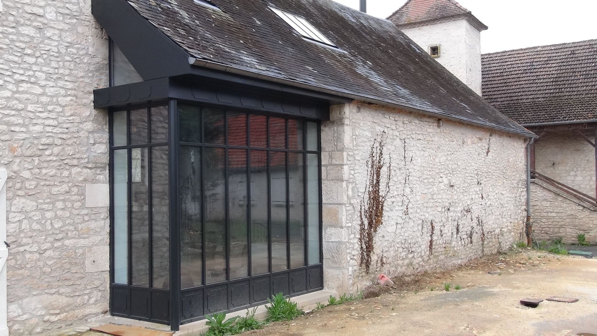 Véranda en ver noire dans maison en pierre