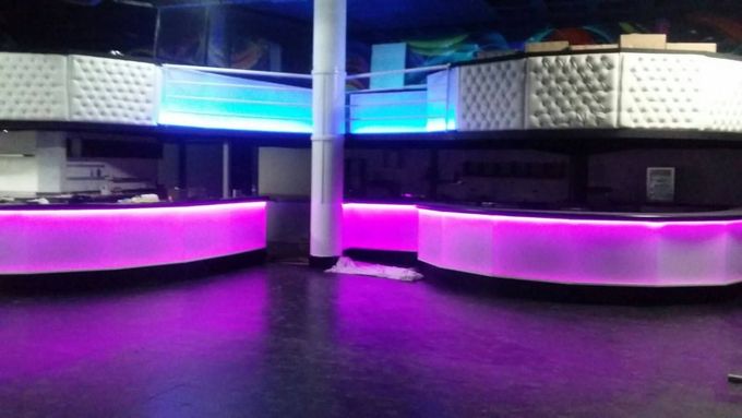 Salón moderno vacío con asientos iluminados con LED morados y azules y un poste central.