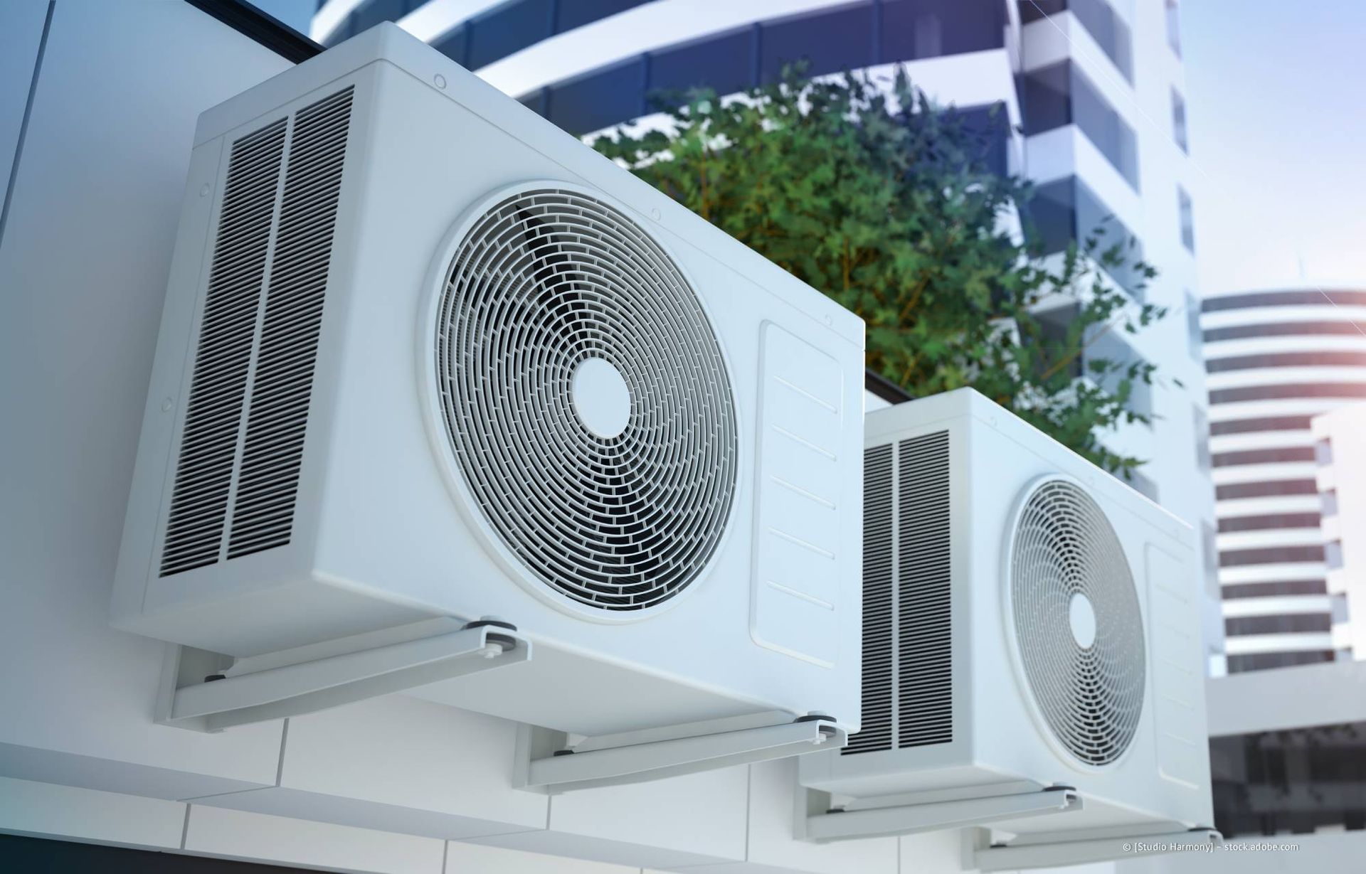 Weiße Klimaanlagen sind an der Seite eines modernen Gebäudes vor einem klaren Himmel angebracht.