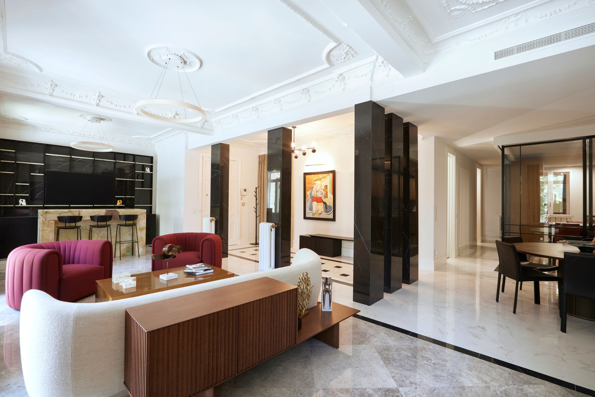 Una sala de estar con un sofá, sillas, una mesa y un televisor.