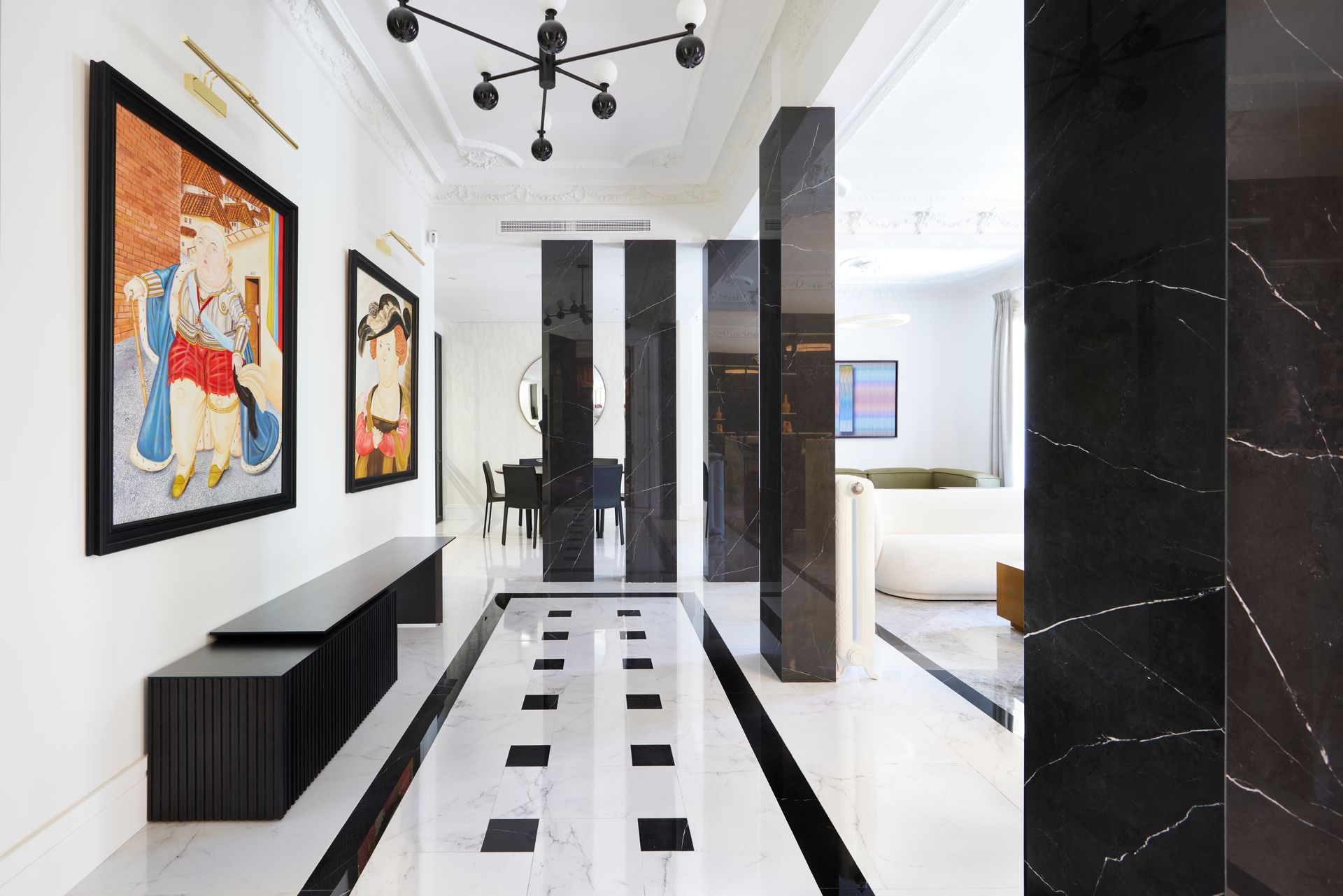 Un pasillo con azulejos blancos y negros y un cuadro en la pared.