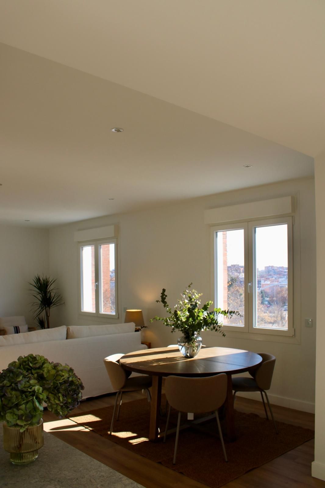 Una sala de estar con una mesa y sillas y un jarrón de flores.