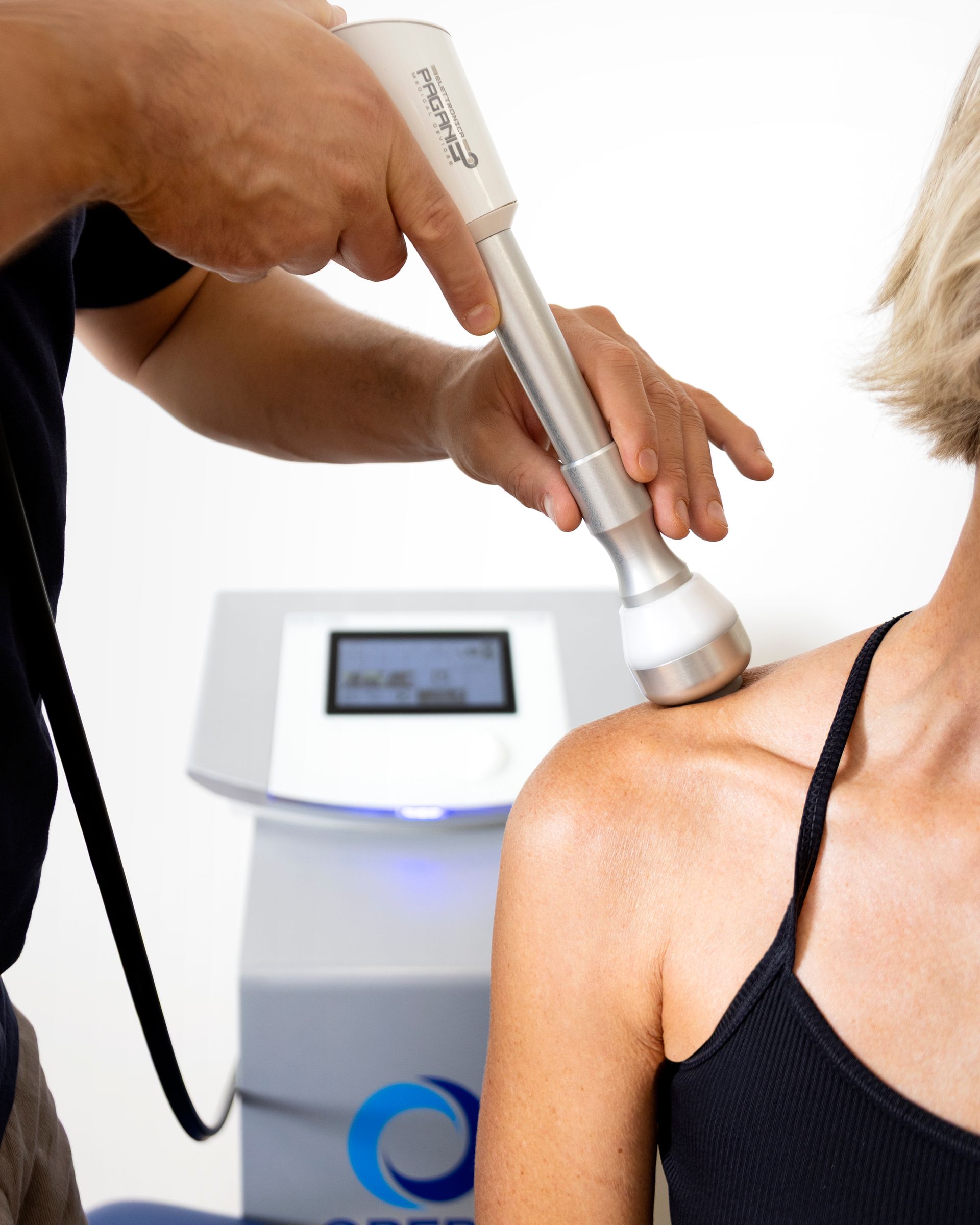 Terapista che utilizza un dispositivo medico sulla spalla di un paziente in una clinica.