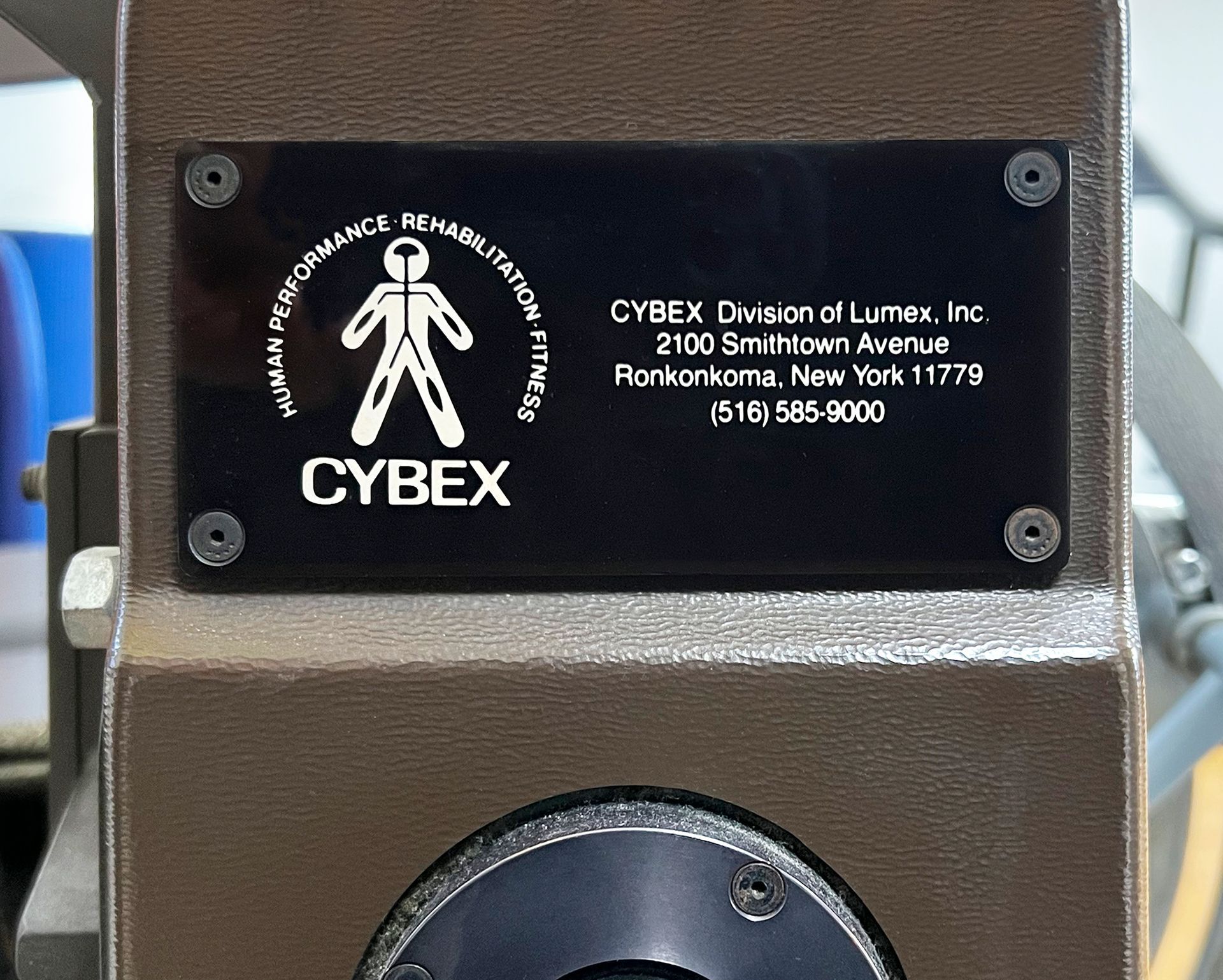 Una targhetta nera dell'attrezzatura Cybex con il logo dell'azienda e le informazioni di contatto.