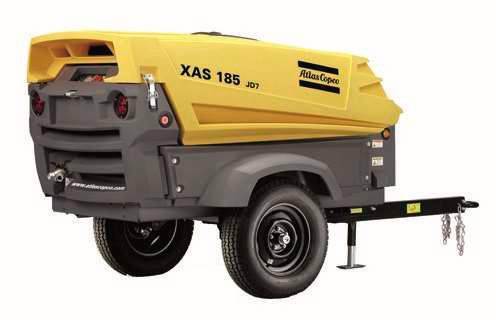 Un tractor rojo acciona una desbrozadora montada lateralmente para recortar la densa vegetación a lo largo de una zanja.