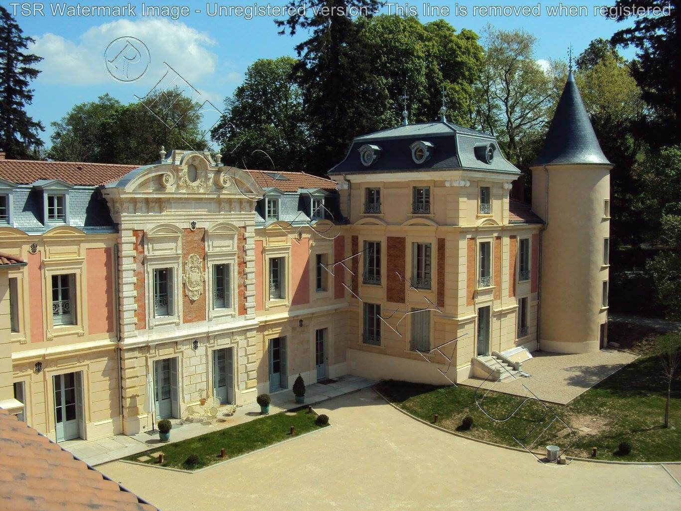 Château historique aux façades couleur pêche, avec une tour conique et une cour ensoleillée sous un ciel bleu