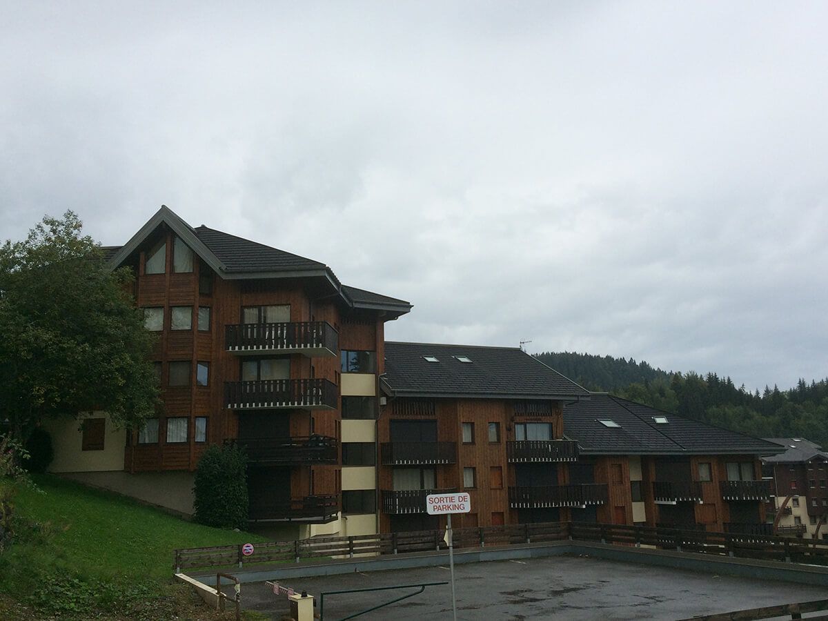 Gîte en briques rouges à plusieurs étages, avec des balcons, sur une colline par temps nuageux