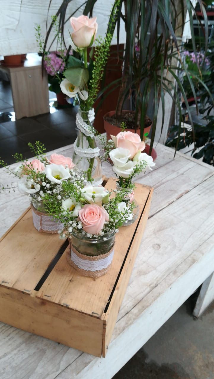 Tischdeko mit weissen und rosa Blumen auf Holzplatte