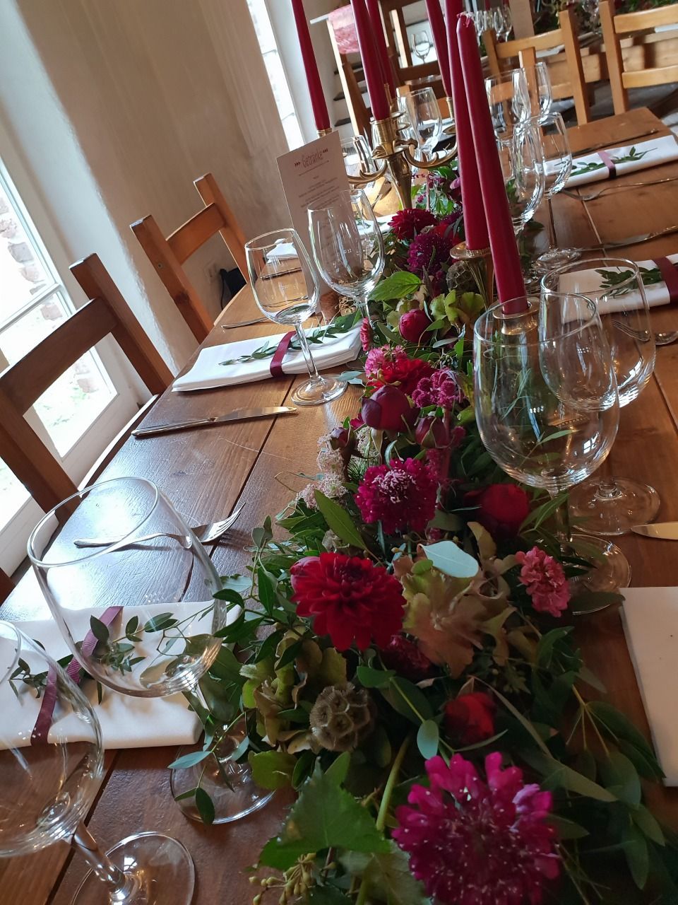 Tischdeko mit roten Blumen und Kerzen