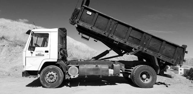 Una fotografía en blanco y negro de un camión volquete con la caja levantada.