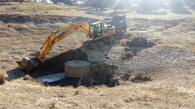 Una excavadora está cavando un hoyo en el suelo de un campo.