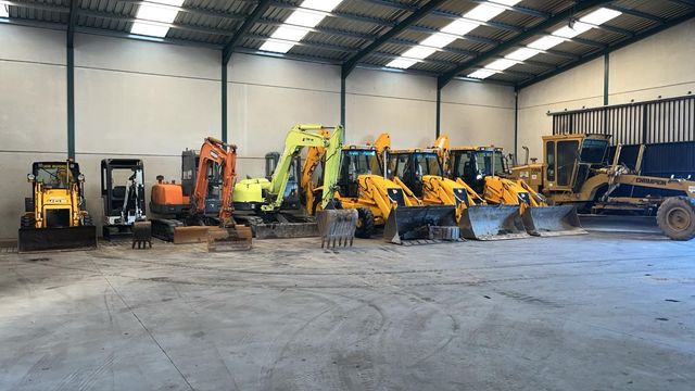 Un almacén lleno de vehículos de construcción amarillos.